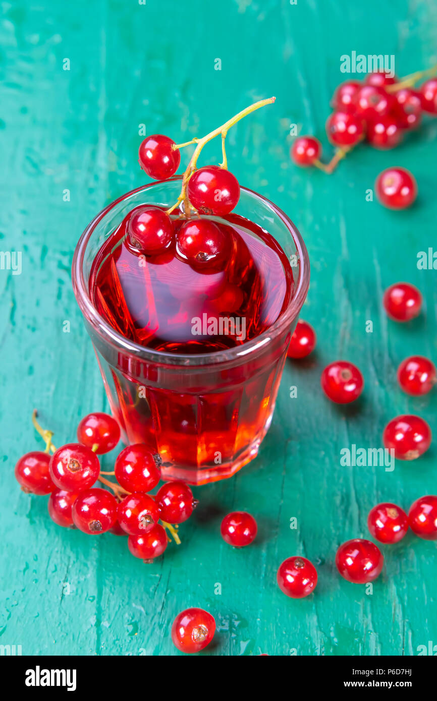 Redcurrant and glass of fruit drink juice on wood table. Focus on redcurrant in glass juice. Stock Photo