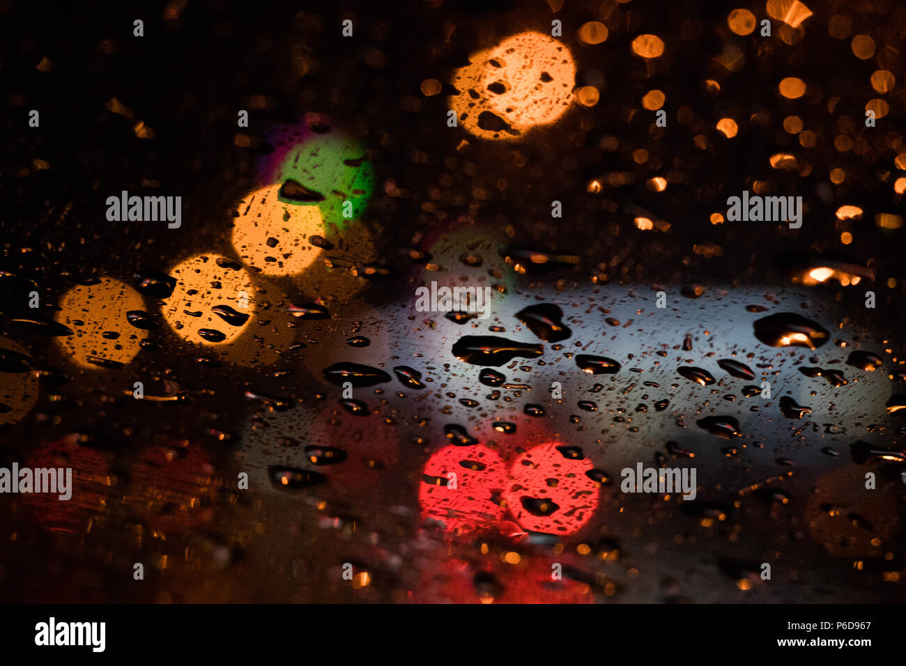 Colorful bokeh shot. Traffic and cars night city road lights and rain drops through the glass. Abstract background Stock Photo