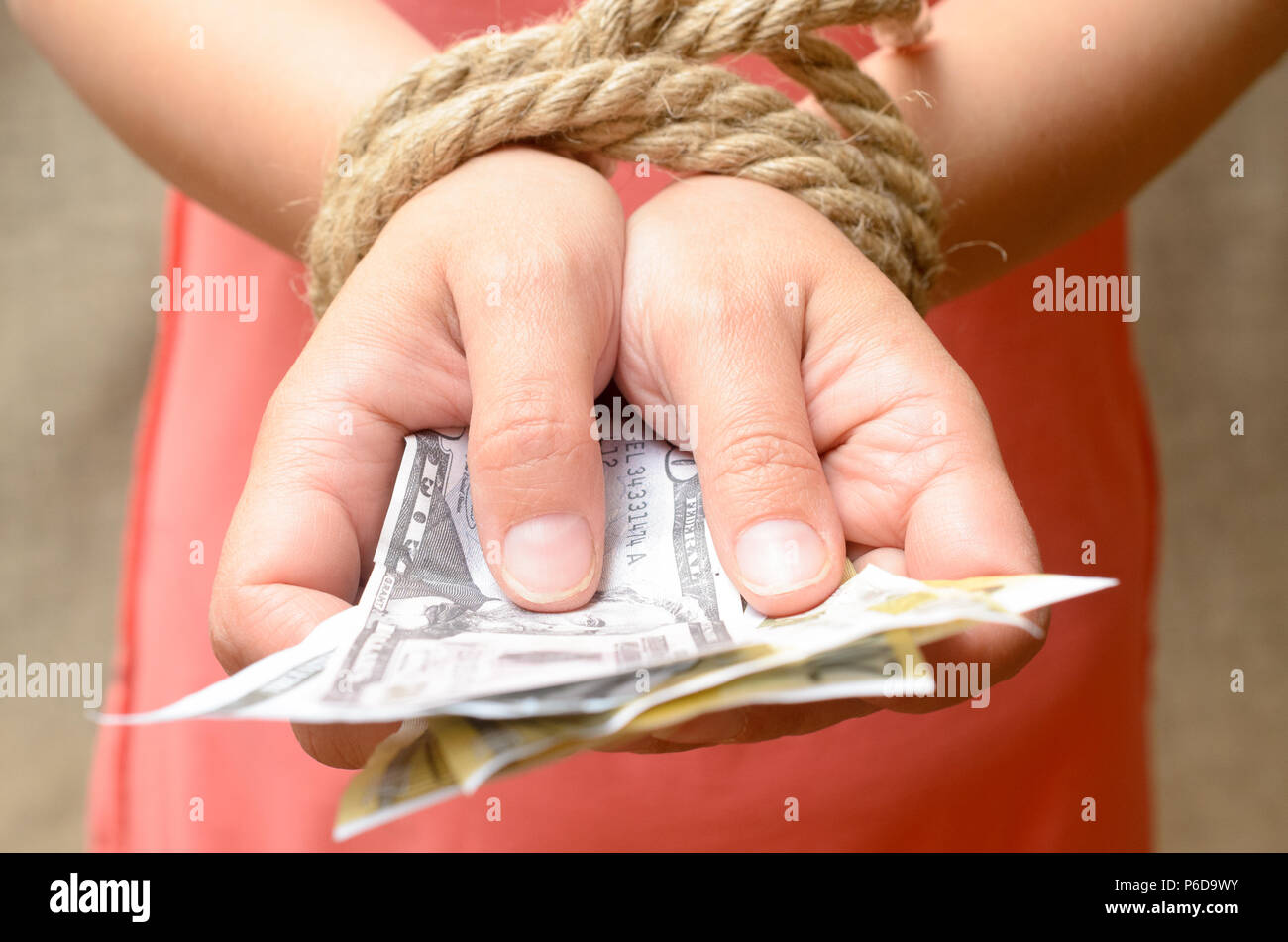 Women's hands tied with a rope and holding money. Credit bondage. Stock Photo