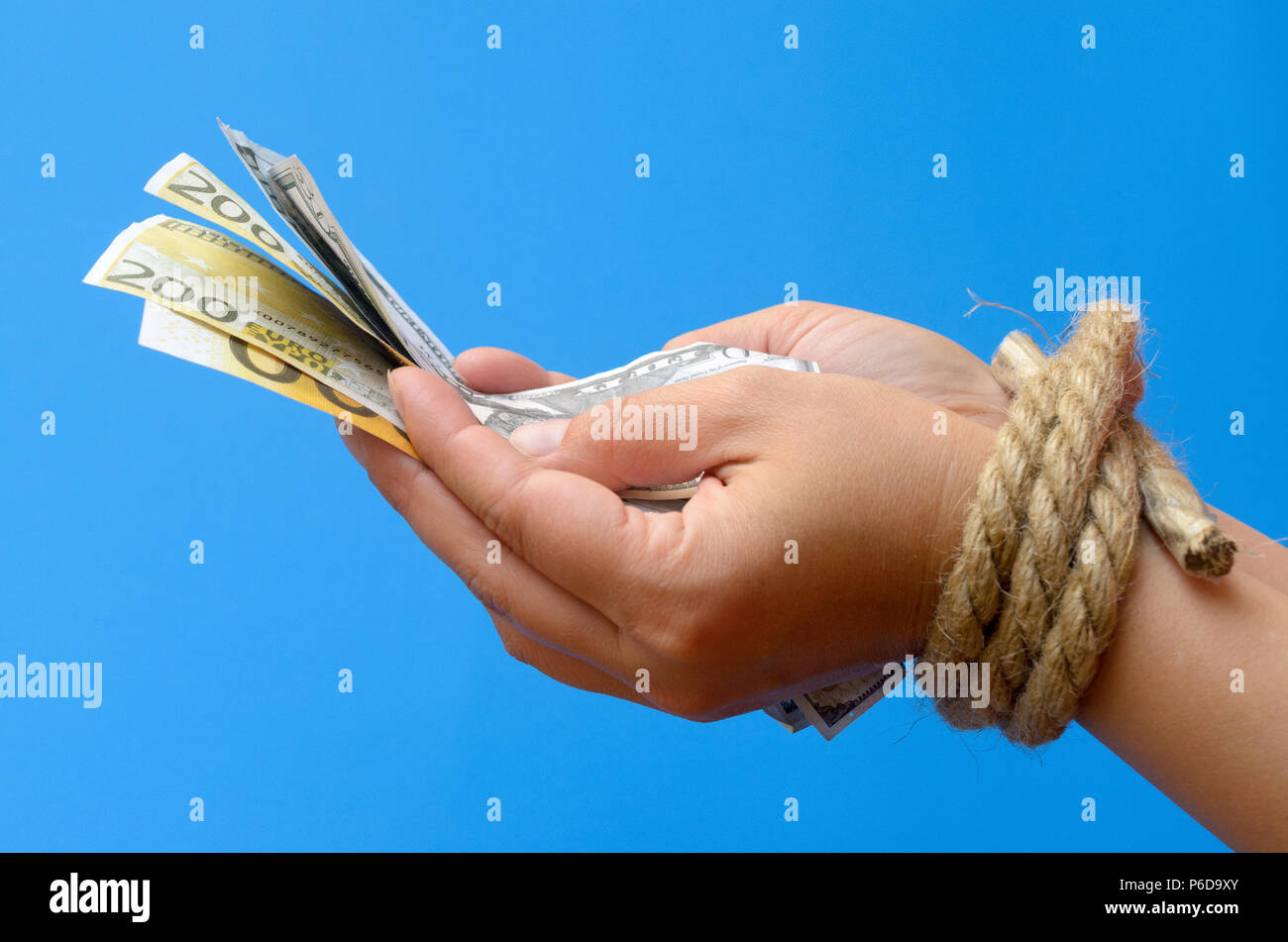 Women's hands tied with a rope and holding money. Credit bondage. Stock Photo