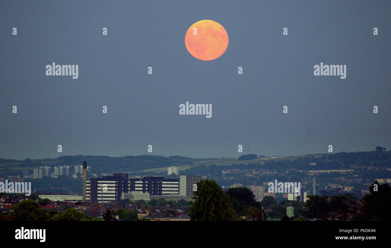 sunny weather clear skies as a Strawberry hot or mead moon or rose moon a full moon over city over yorkhill hospital Cathkin braes and Dechmont hill Stock Photo