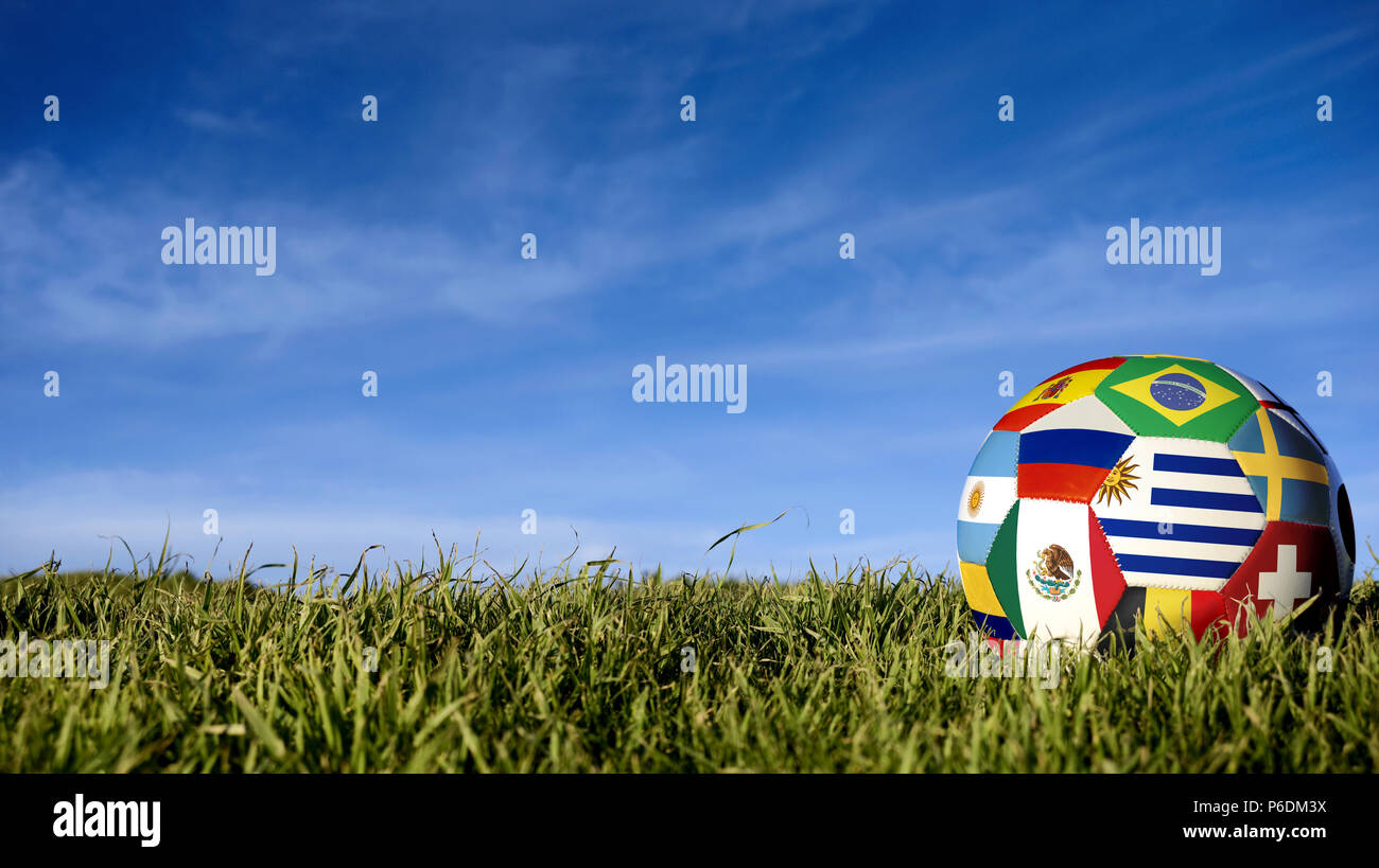 Soccer ball with international country flag of russian sport event groups. Realistic football on grass field over blue sky background. Includes urugua Stock Photo
