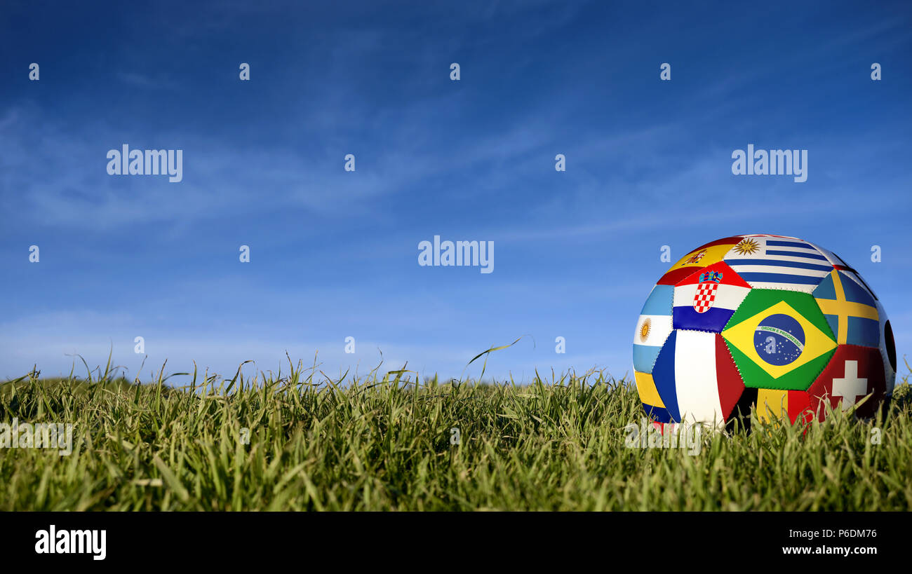 Soccer ball with international country flag of russian sport event groups. Realistic football on grass field over blue sky background. Includes brazil Stock Photo