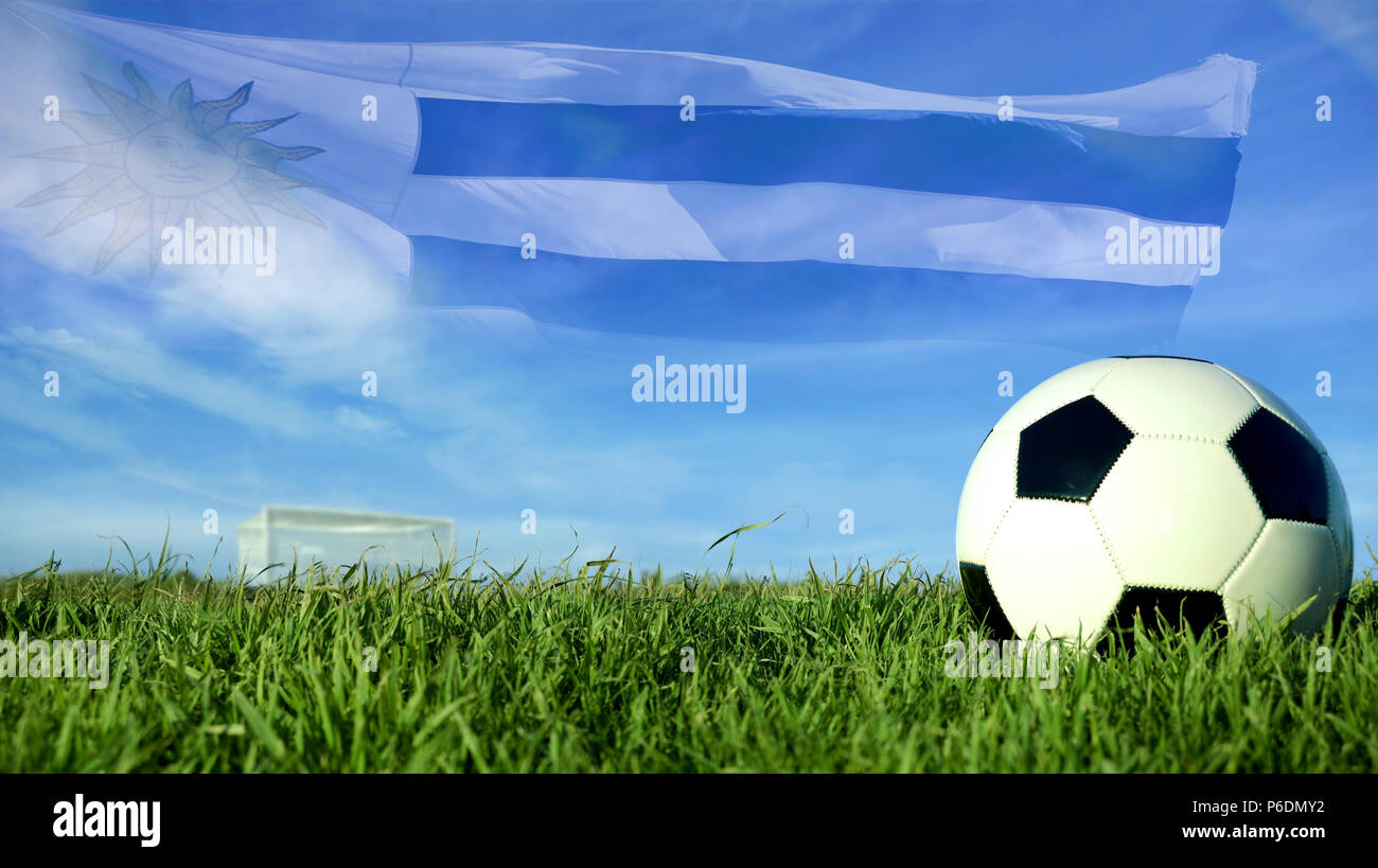 Soccer ball with Uruguay flag for sport event, Uruguayan team celebration. Realistic leather football on goal post field over blue sky background. Stock Photo