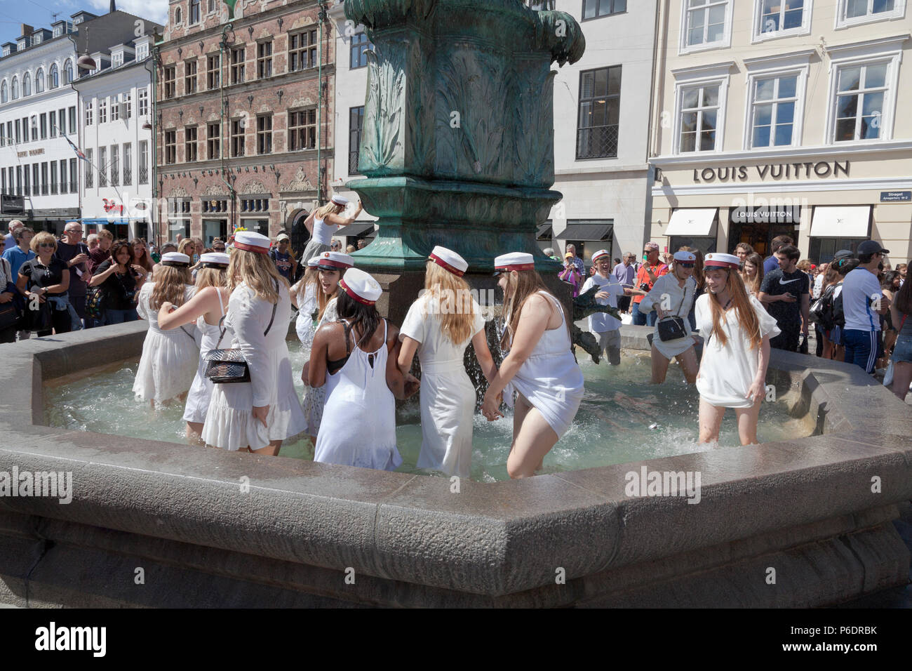 Copenhagen, Denmark. June 29, 2018. Danish students celebrate their high school / grammer school graduation and take the plunge. A dance around and a dip or dive into the cold water of the Stork Fountain (Storkespringvandet) on the pedestrian street, Stroeget, is a traditional element on the day of celebration for  graduated students in Greater Copenhagen. It is often part of the long, exhausting and high-spirited truck tour visiting each student’s home for refreshments. Credit: Niels Quist/Alamy Live News Stock Photo