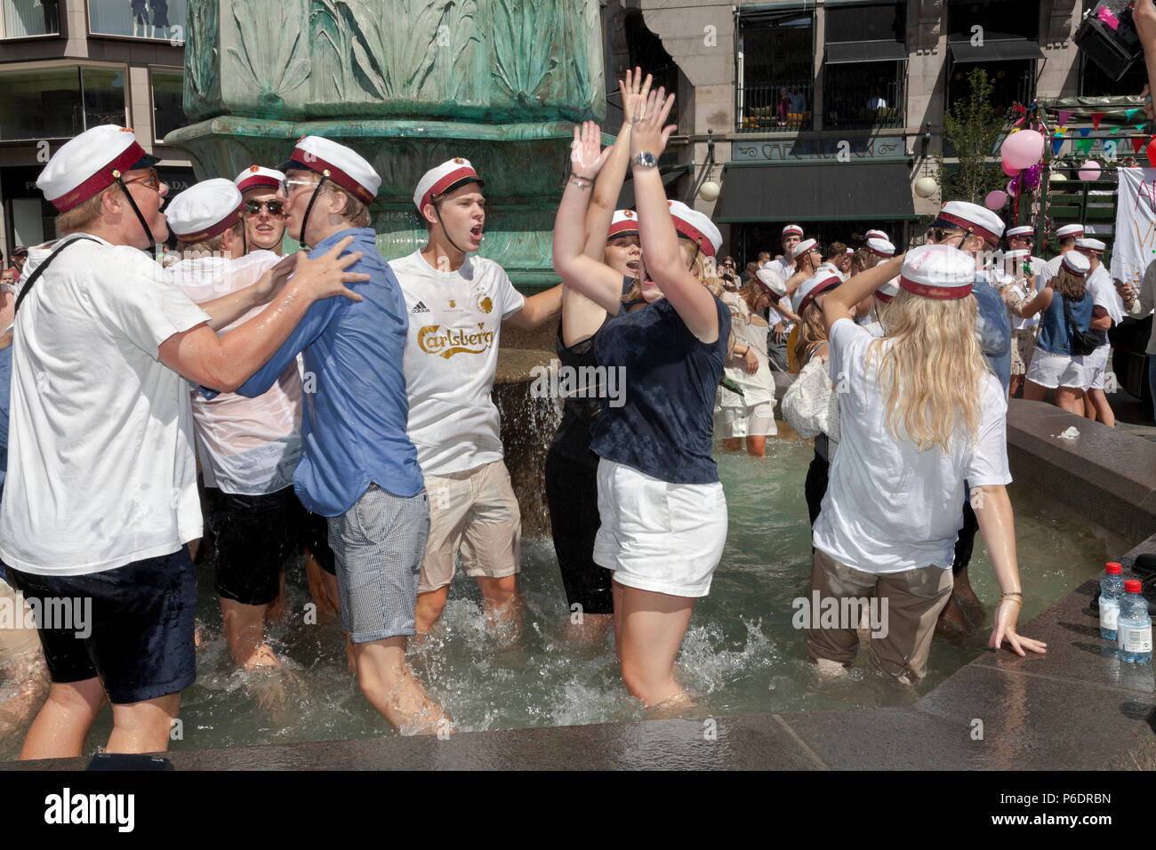 Copenhagen, Denmark. June 29, 2018. Happy, Danish students celebrate their high school, grammar school graduation and take the plunge. A dance around and a dip or dive into the cold water of the Stork Fountain (Storkespringvandet) on the pedestrian street, Stroeget, is a traditional element on the day of celebration for  graduated students in Greater Copenhagen. It is often part of the long, exhausting and high-spirited truck tour visiting each student’s home for refreshments. Credit: Niels Quist/Alamy Live News Stock Photo