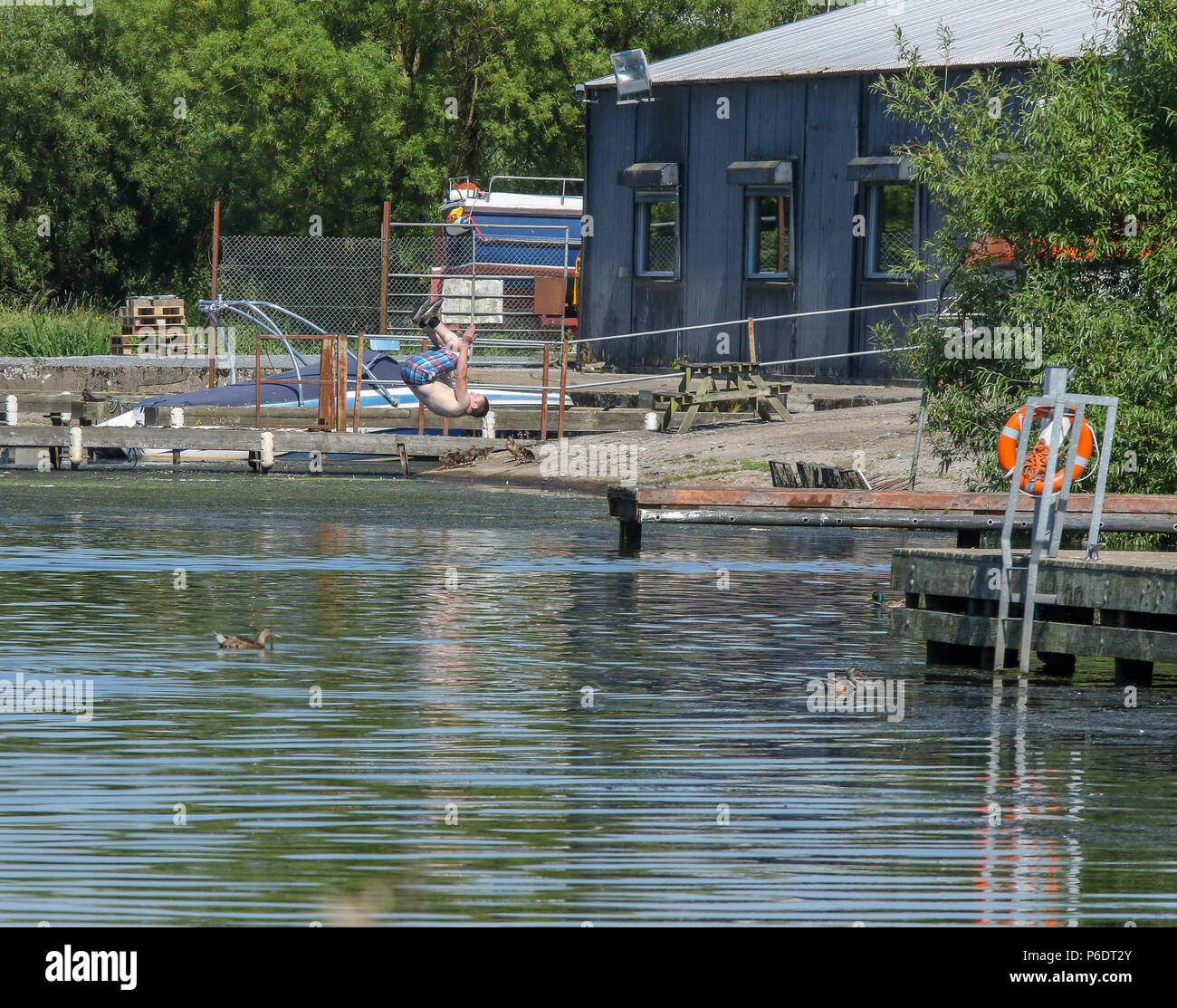 Lough Neagh, Northern Ireland. 29 June 2018. UK weather - another glorious summer day as the heatwave continues. Lough Neagh is the UK's largest freshwater lake and with weather like this it's a great place to enjoy the best summer in decades. A young man somersaulting into the water at Kinnego marina. Credit: David Hunter/Alamy Live News. Stock Photo
