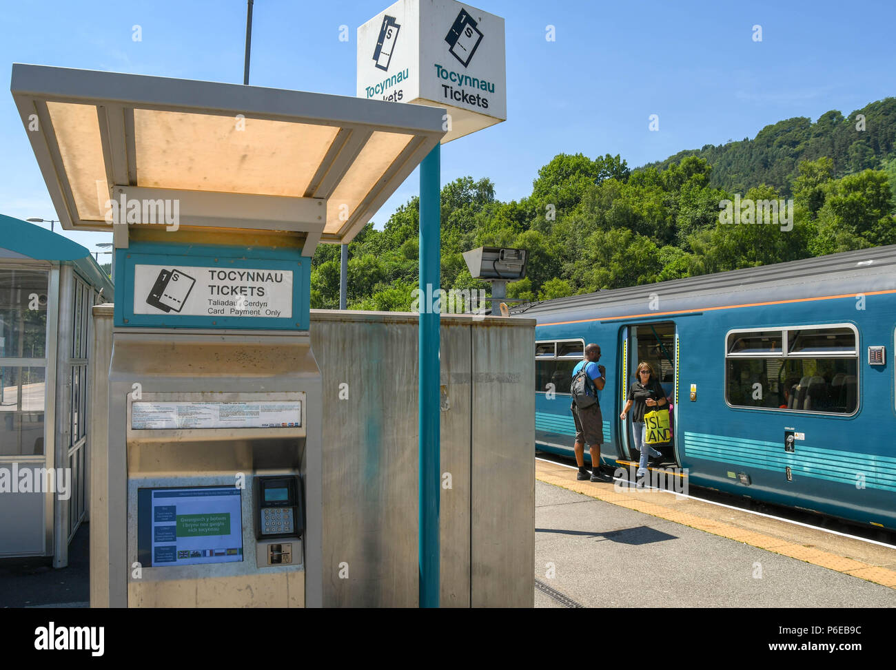 Wide angle view of a ticket machine on the platform at Abercynon railway station in south Wales. People are getting off a train in the background. Stock Photo