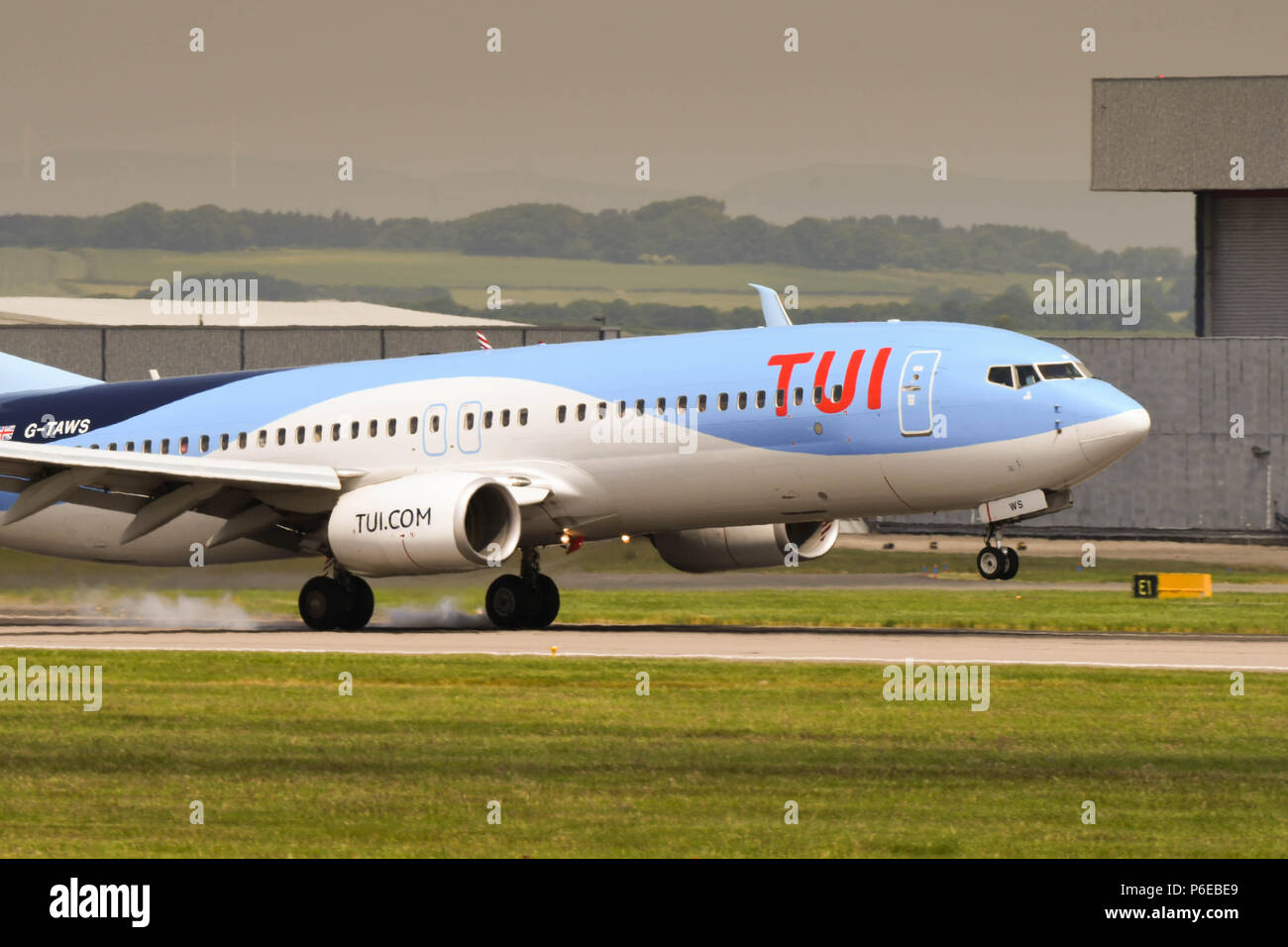 Smoke from the wheels of a Boeing 737 of the holdiay airline TUI as it touches down in Cardiff Wales Airport Stock Photo