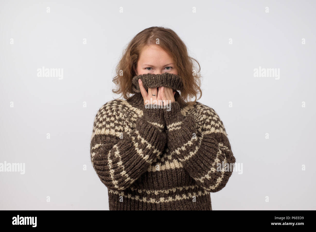 Woman in warm brown sweater hiding her face. Only eyes are seen. She wants to stay anonym. Stock Photo