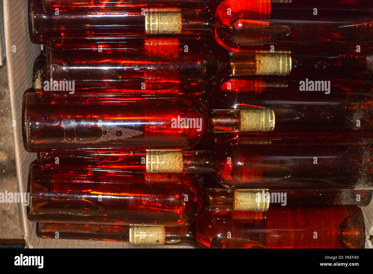 Bottles of domestic wine. Resting wine bottles stacked on iron racks in cellar. Stock Photo
