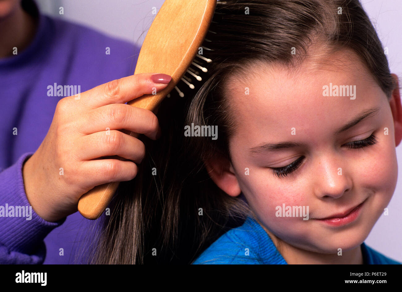 Mother brushing daughters hair getting ready to go to school. Stock Photo