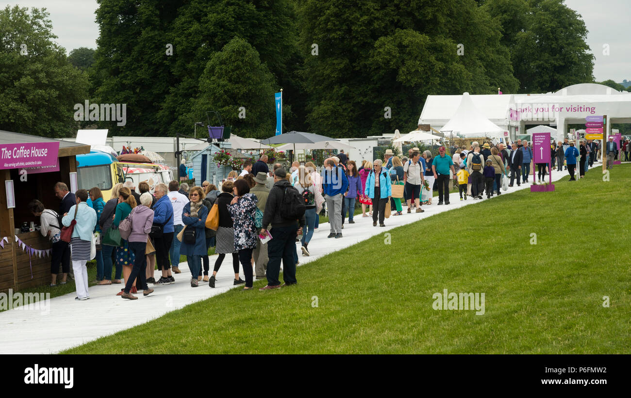 Large crowd of people at showground, walking near entrance, past trade stands & exhibits at busy RHS Chatsworth Flower Show, Derbyshire, England, UK. Stock Photo