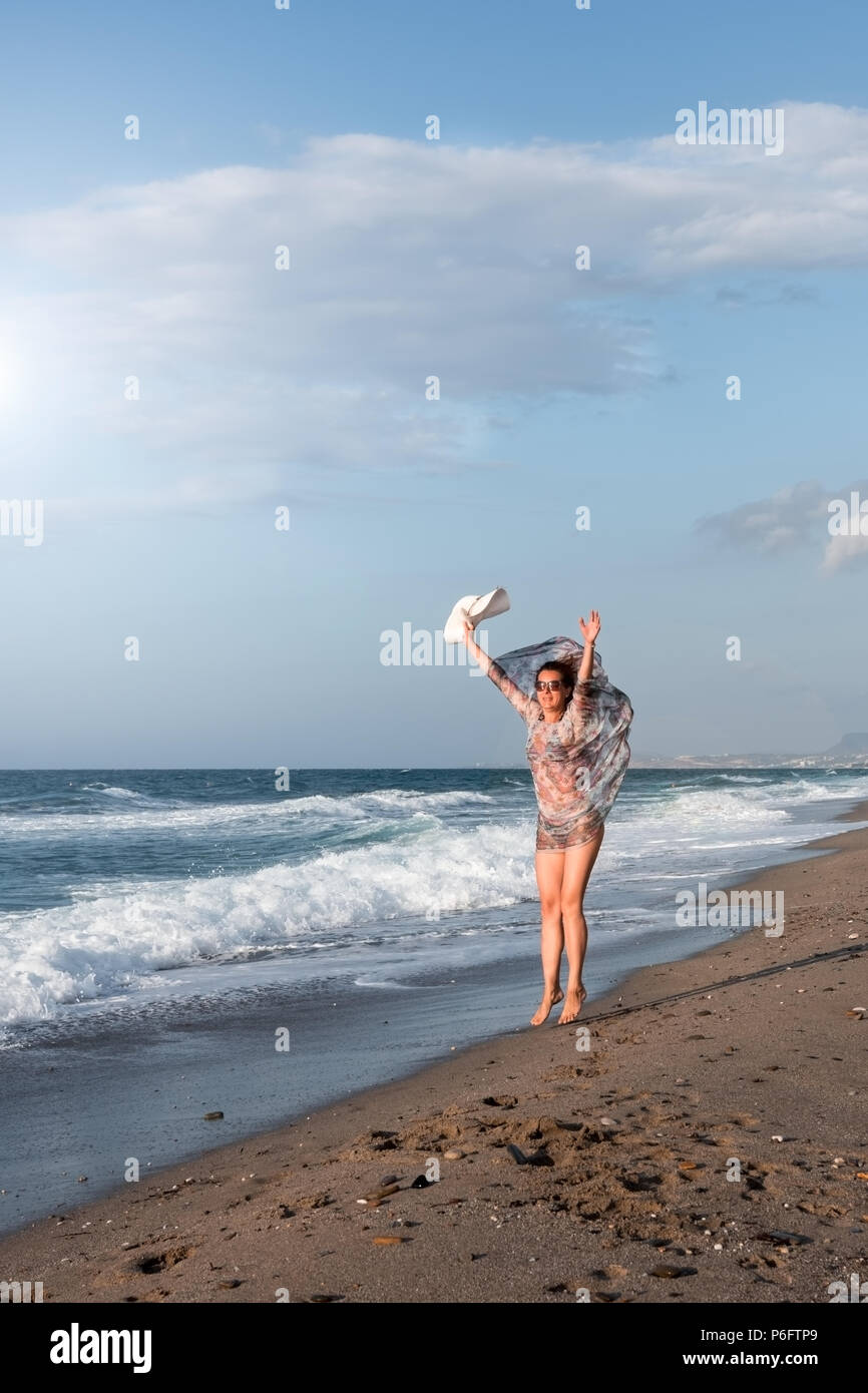 Woman jumping on the beach by the seashore Stock Photo