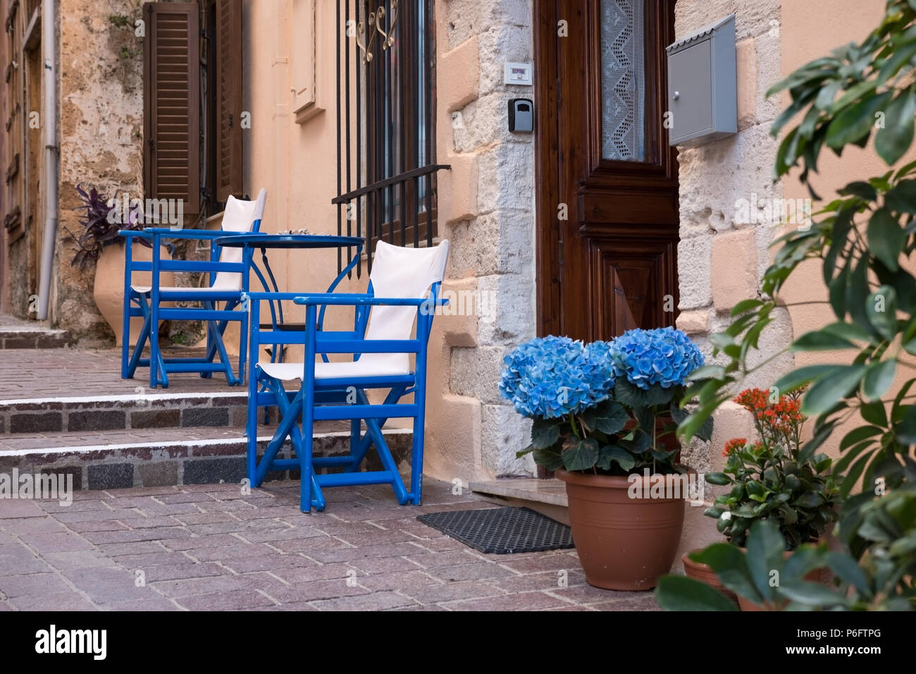 Resting place with blue chairs on the narrow street in Greece Stock Photo