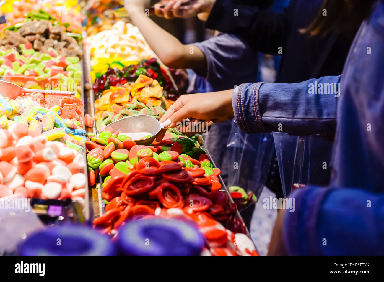 Customers choose sweets from counter with assorted colorful different