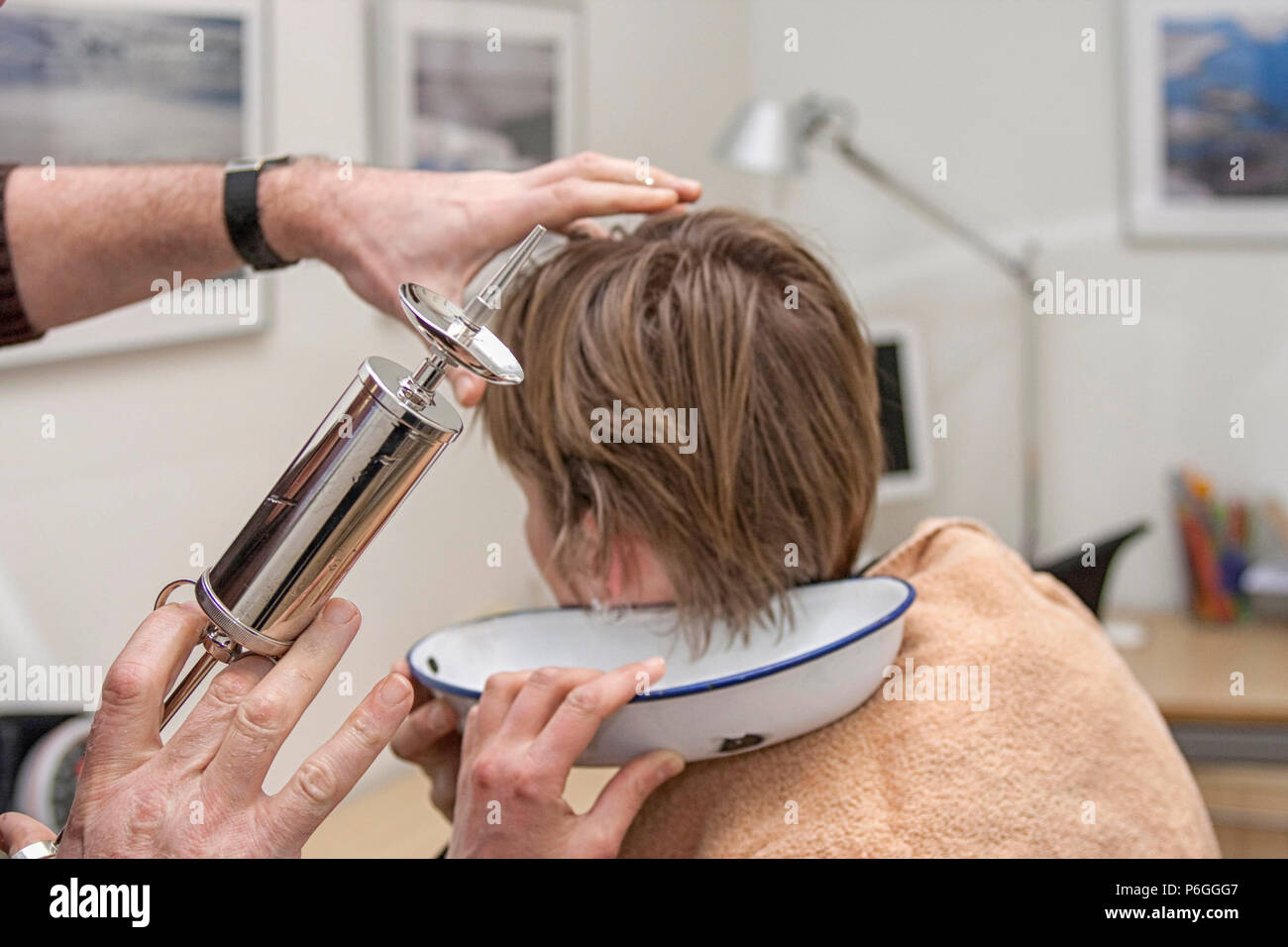 Doctor with big syringe ready to clean ear of woman Stock Photo Alamy