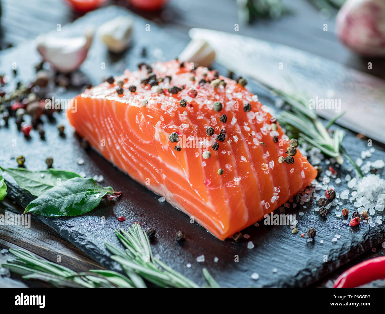 Fresh salmon fillet on black cutting board with herbs and spices Stock ...