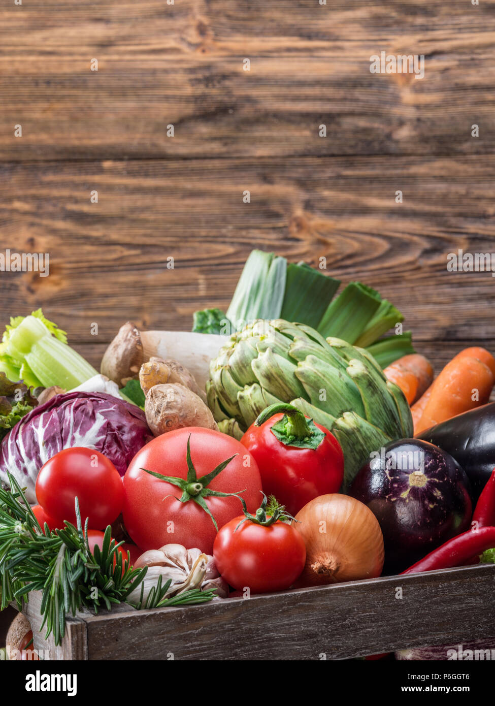 Fresh multi-colored vegetables in wooden crate. Wooden background. Stock Photo