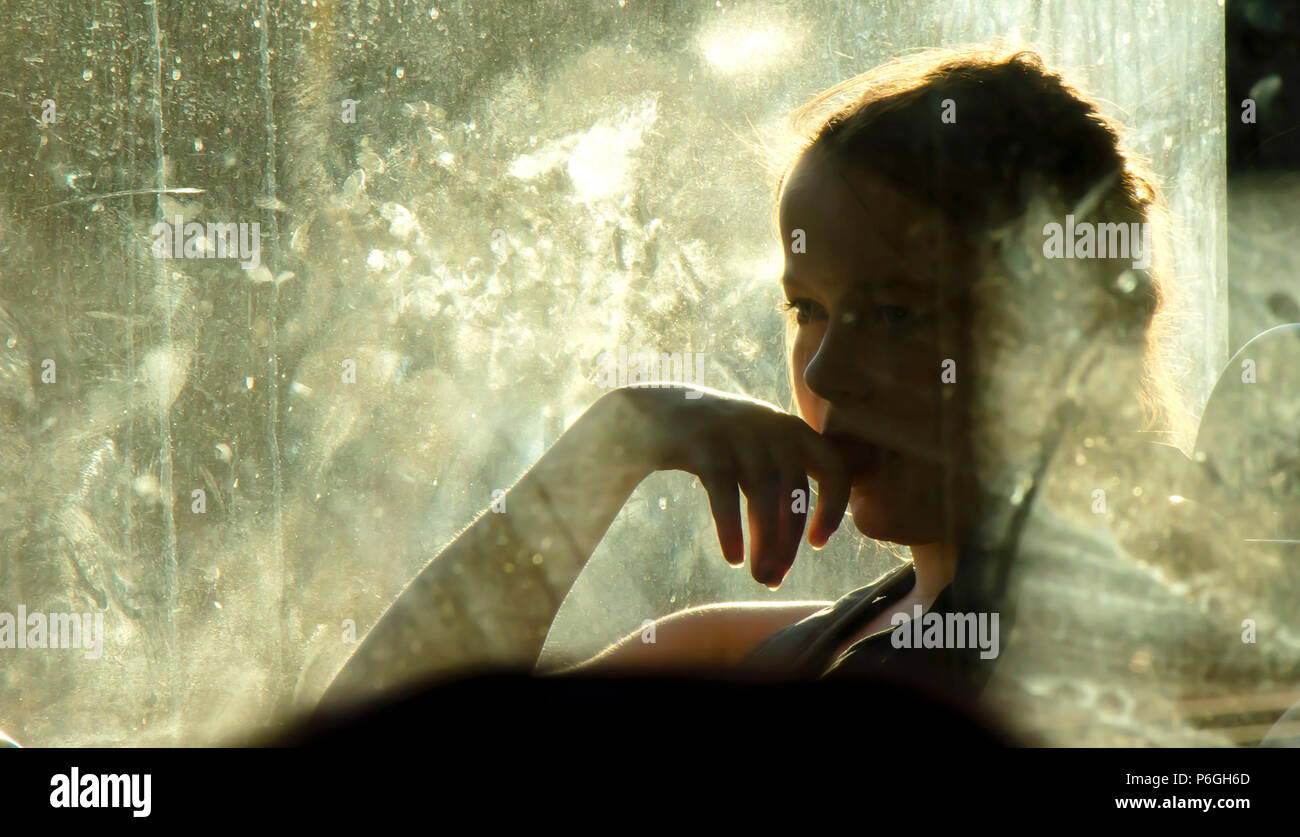 Belgrade, Serbia - May 29, 2018 : Blurry soft portrait of young blond teenage girl sitting and daydreaming while riding in a window seat of a bus on a Stock Photo