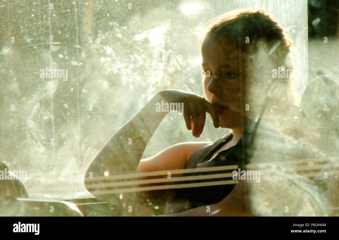 Belgrade, Serbia - May 29, 2018 : Blurry soft portrait of young blond teenage girl sitting and daydreaming while riding in a window seat of a bus on a Stock Photo