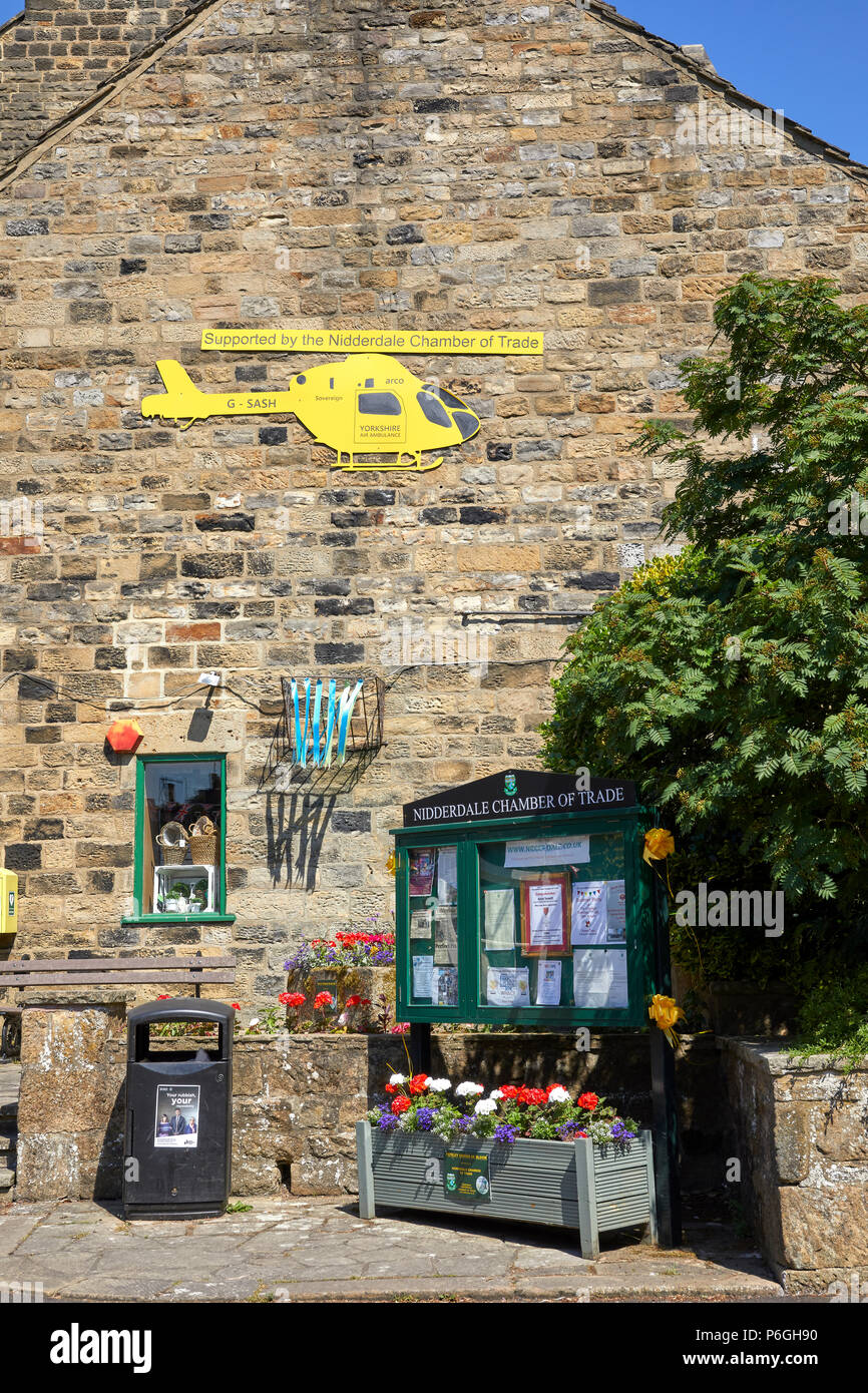 Pateley Bridge Chamber of Trade notice board and Yorkshire Air Ambulance sponsorship wall end design. Nidderdale, North Yorkshire Stock Photo