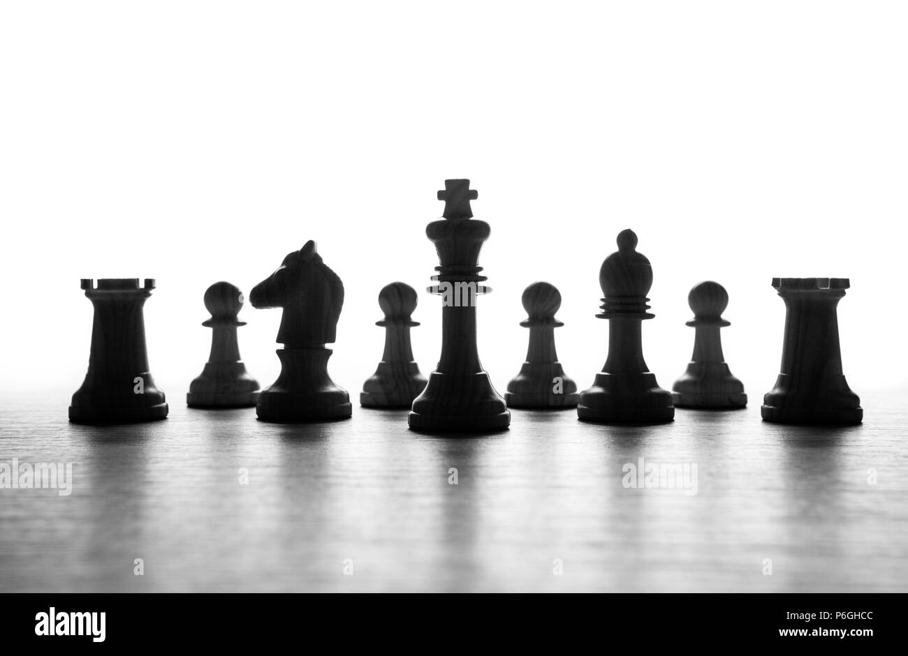 black-and-white chess pieces lined up in a row on a white background ...