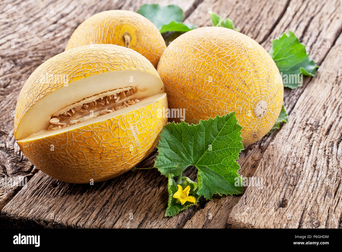 Ripes melons with melon leaves on wooden background. Stock Photo