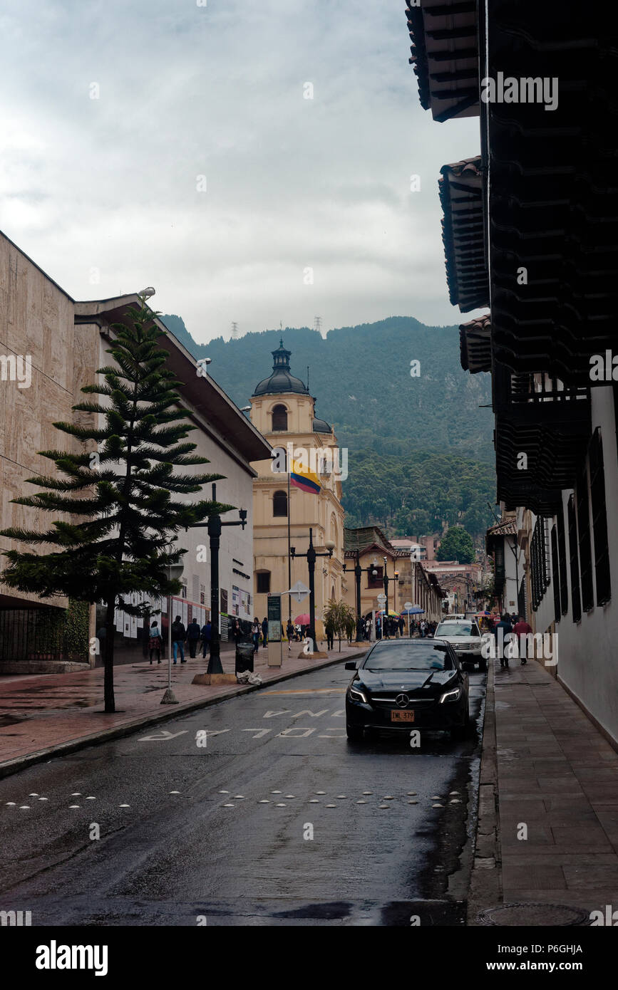 Damp street in Bogota, Colombia, with a church spire pointing to the maontains Stock Photo