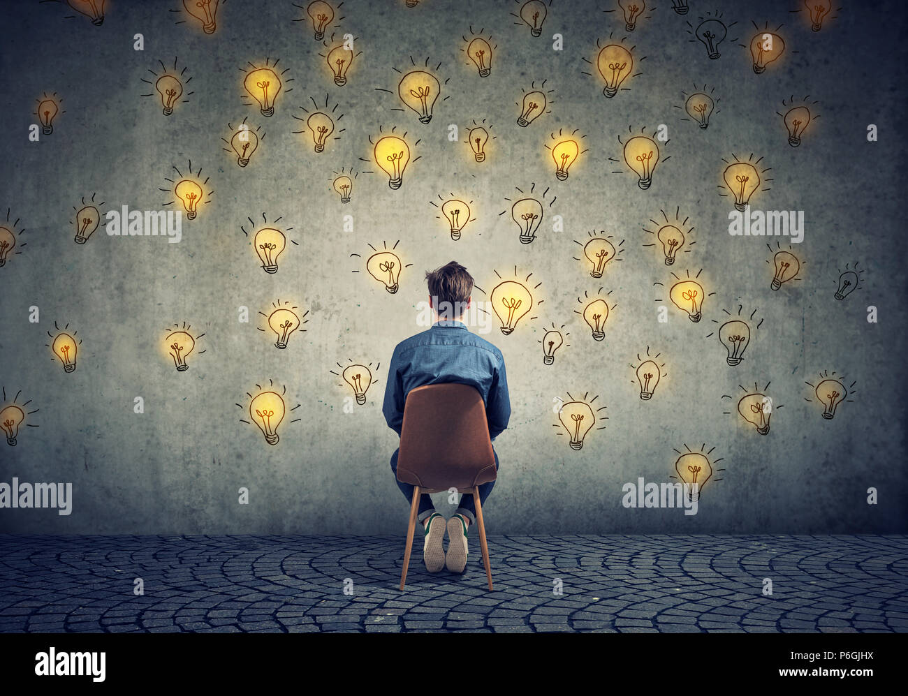Man sitting on a chair has many bright ideas looking at wall making decisions Stock Photo