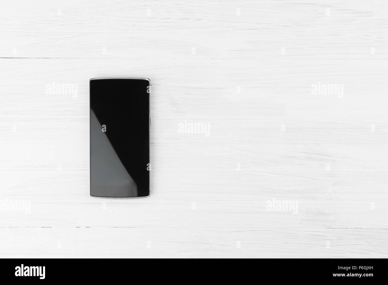 Black Smart Phone On White Wood Background With Empty Space For Text Top Angle Stock Photo