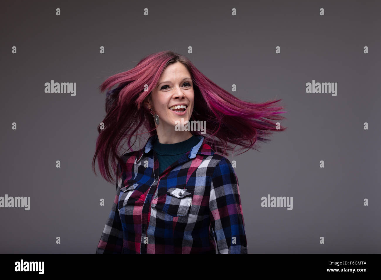 Carefree Laughing Woman In A Stylish Plaid Top Flicking Her Long