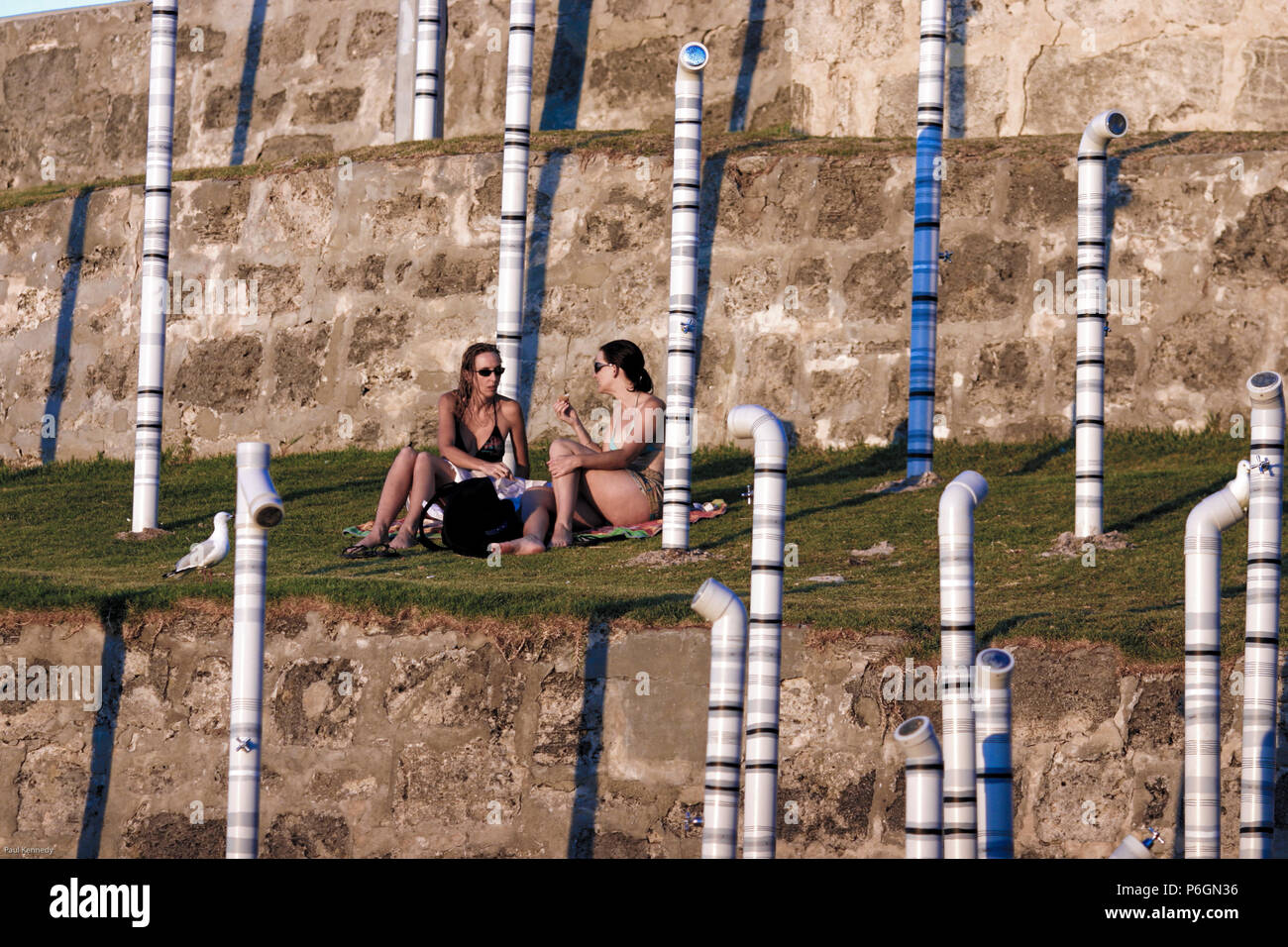 Women sit amongst sculptures on Cottesloe Beach in Perth, Australia Stock Photo