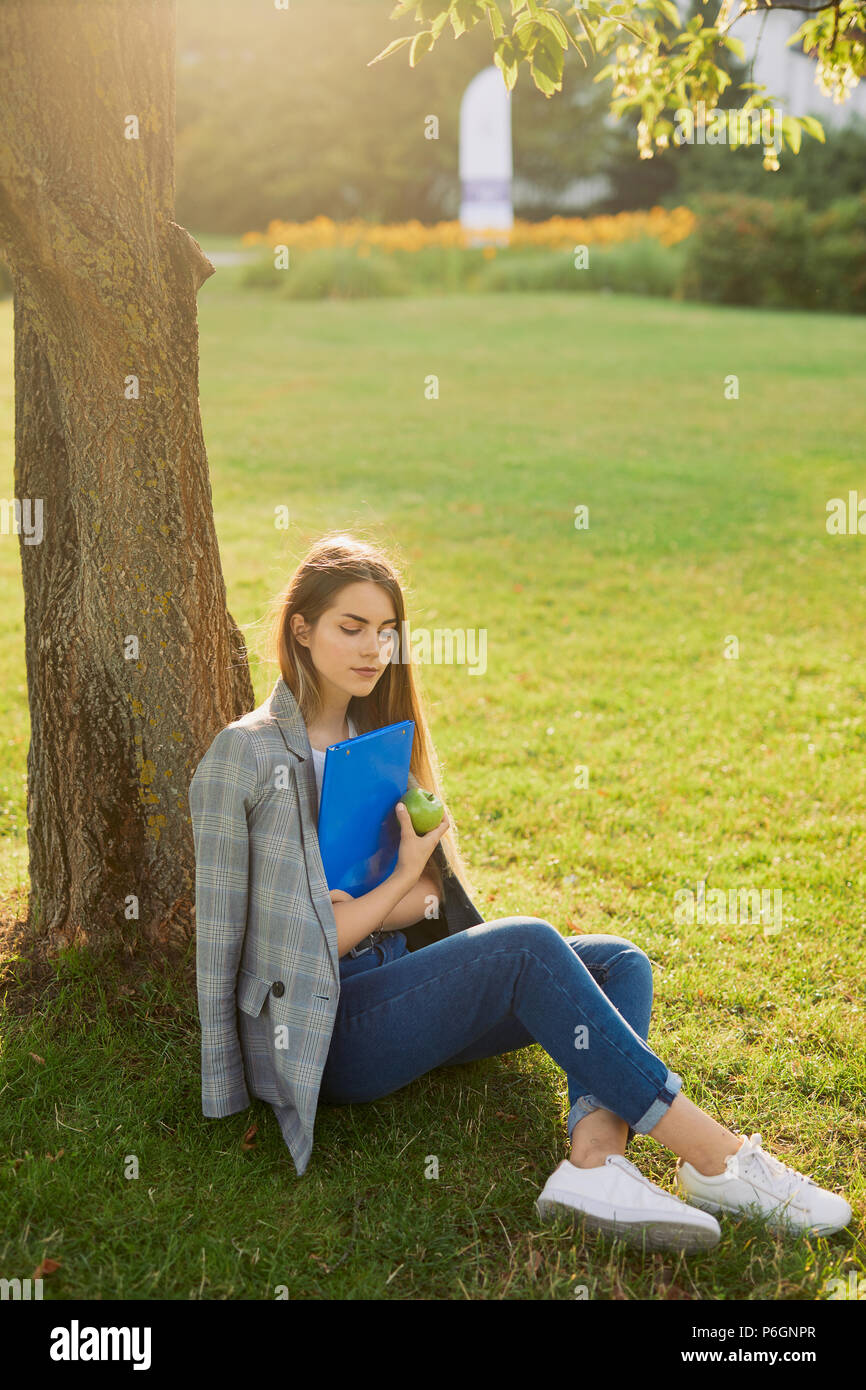 Pretty girl with her book in park background, sunset Stock Photo - Alamy