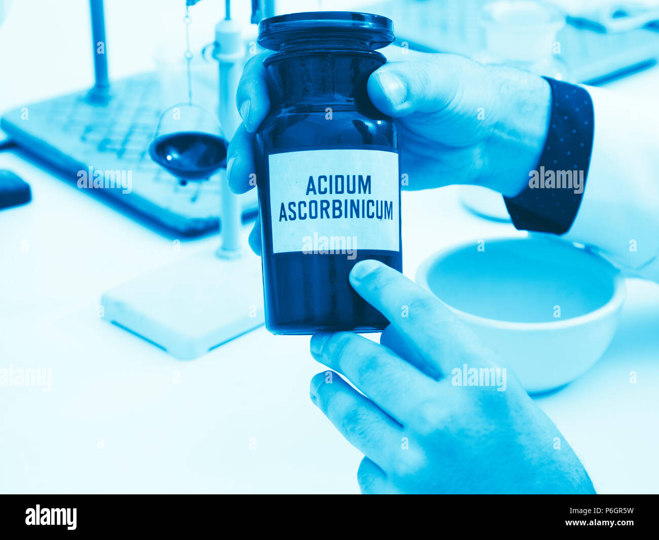 A scientist or pharmacist holds a bottle of ascorbic acid with an inscription in Latin: Acidum ascorbinicum Stock Photo