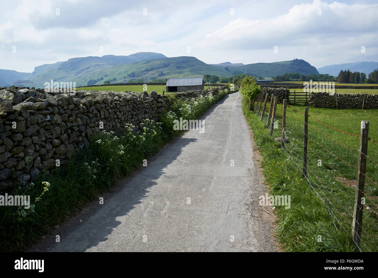 tarmaced country lane bounded by dry stone wall and wire fence in rural underskiddaw keswick cumbria england uk Stock Photo