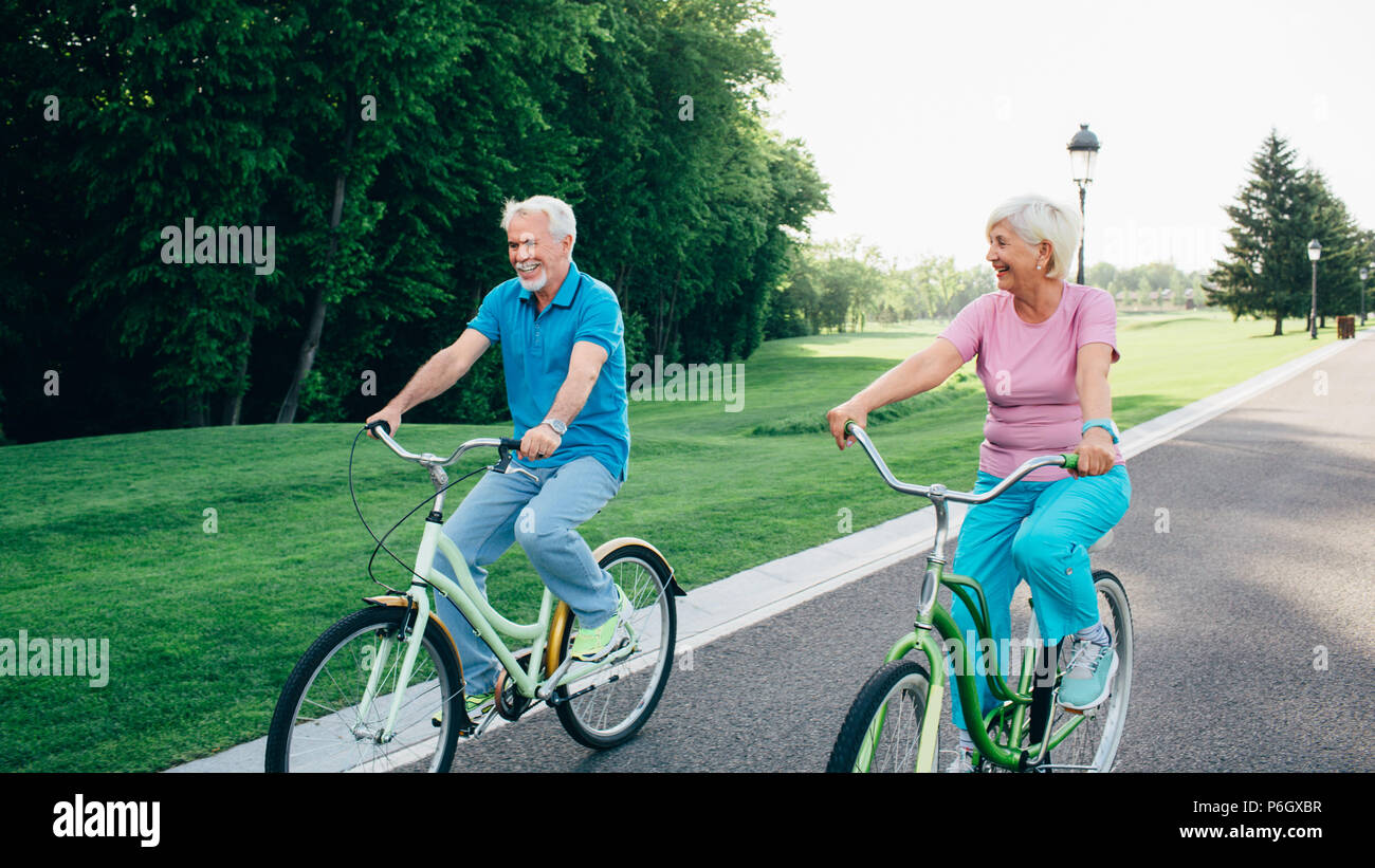 Senior couple riding bicycles on green park Stock Photo