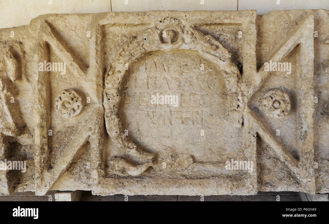 Latin inscription, limestone. Shuni. Roman period, 2nd century AD. The  inscription is surrounded by a wreath. The goddes of victory, Nike, is seen  standing on a globe on both sides of the