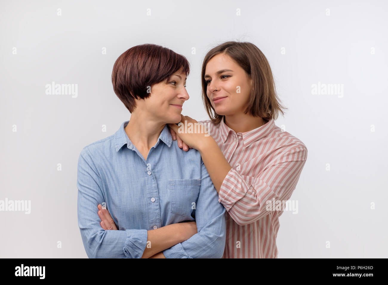 Beautiful maturesenior mom and her adult daughter are hugging, looking at camera and smiling. Stock Photo