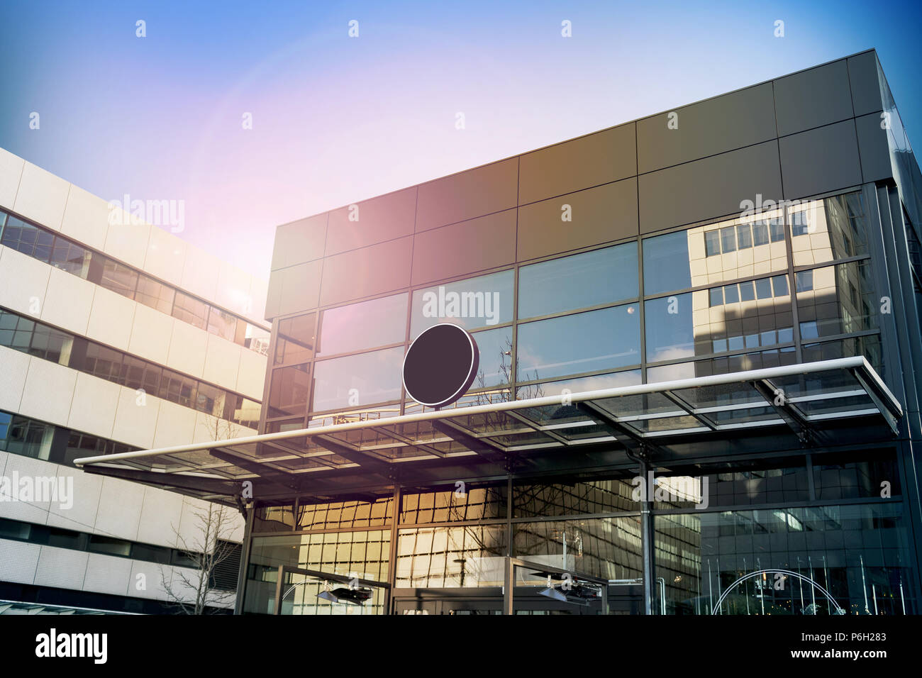 Blank black round signage mockup, modern business building. Circle sign board mock up hanging on glass roof of the store endrance. Street advertising banner design template. Stock Photo
