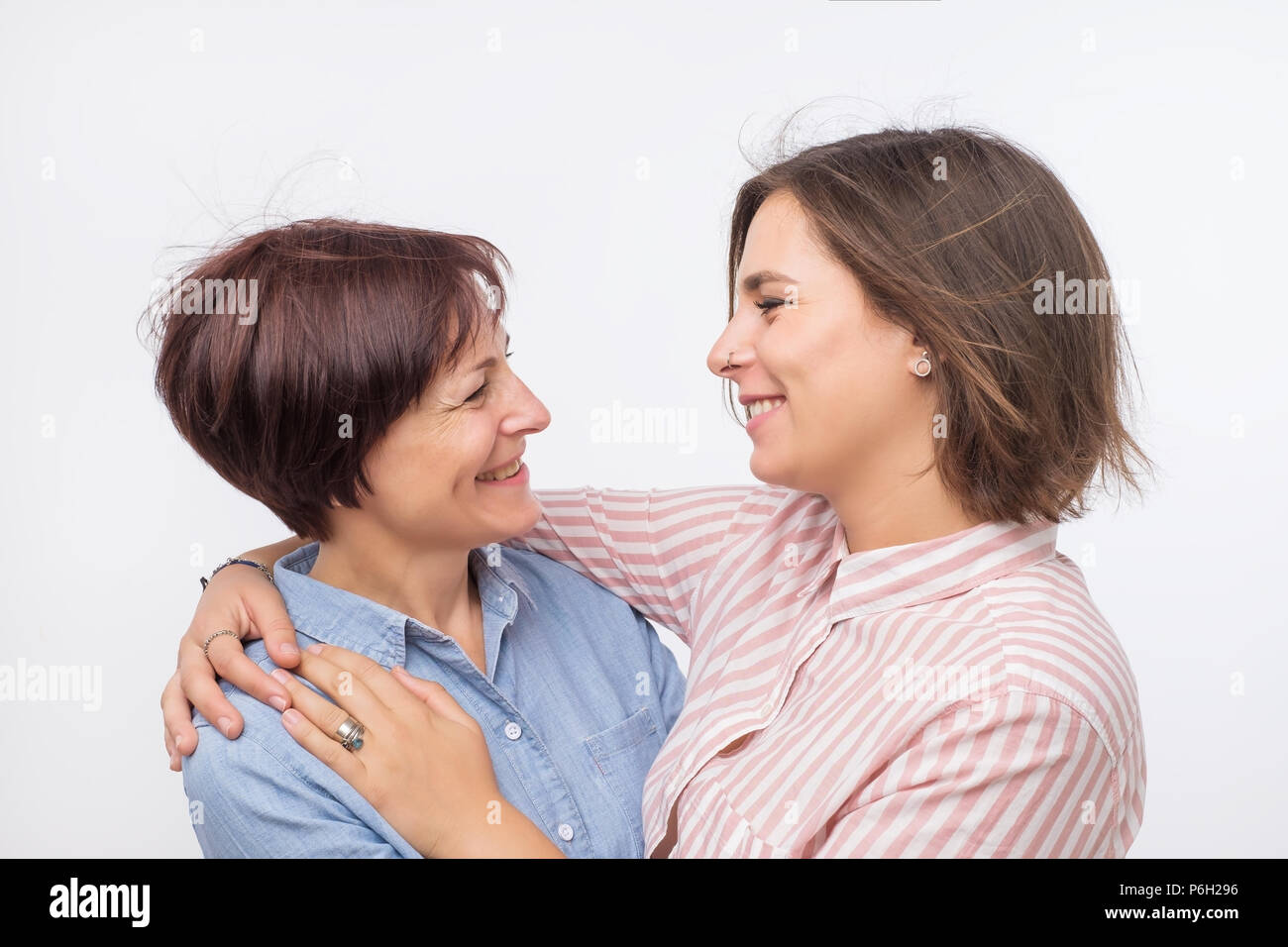 Beautiful maturesenior mom and her adult daughter are hugging, looking at camera and smiling. Stock Photo