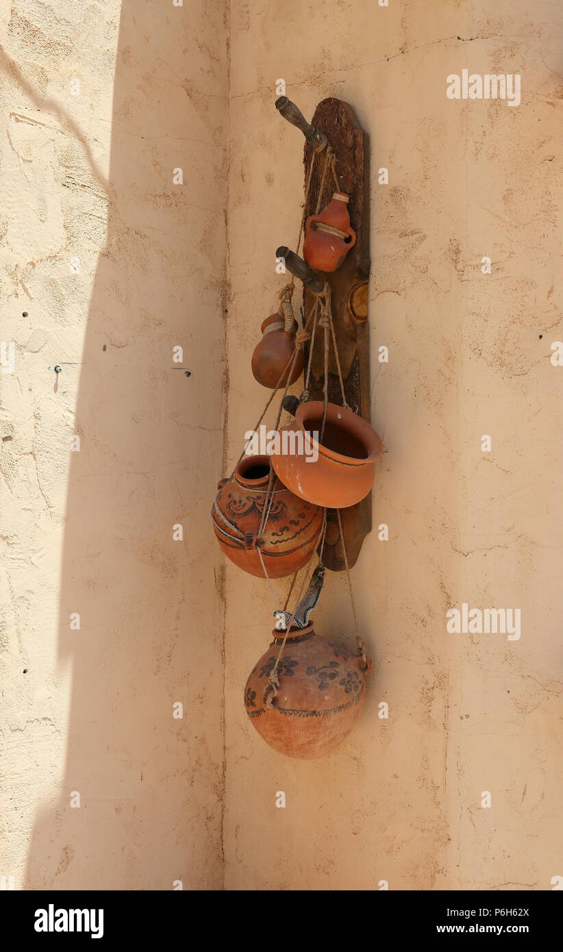 Terra cotta pots hanging on the shady side of an adobe wall Stock Photo