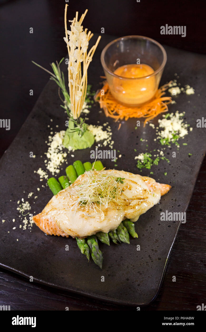 Grilled salmon served with asparagus. It is garnished and served with a glass of Sriracha mayo. Stock Photo