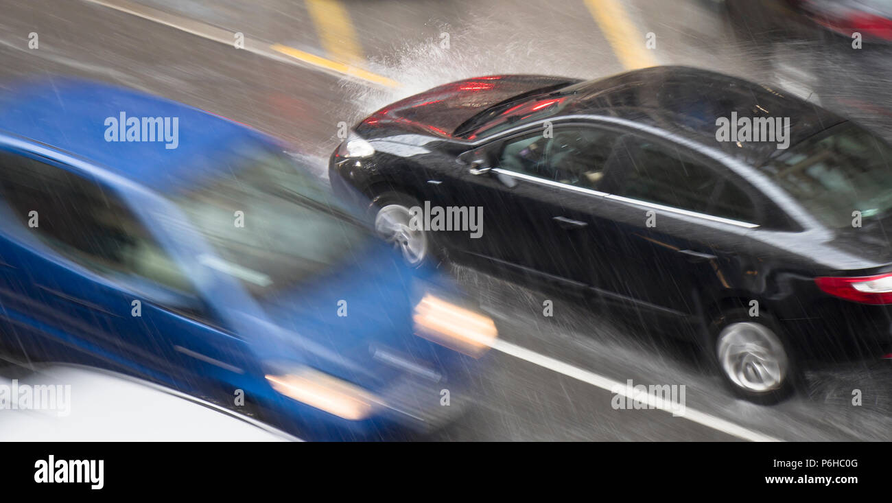 Blurry driving car in the street hit by the heavy rain with hail, in rainy spring season in motion blur panning shot from above Stock Photo