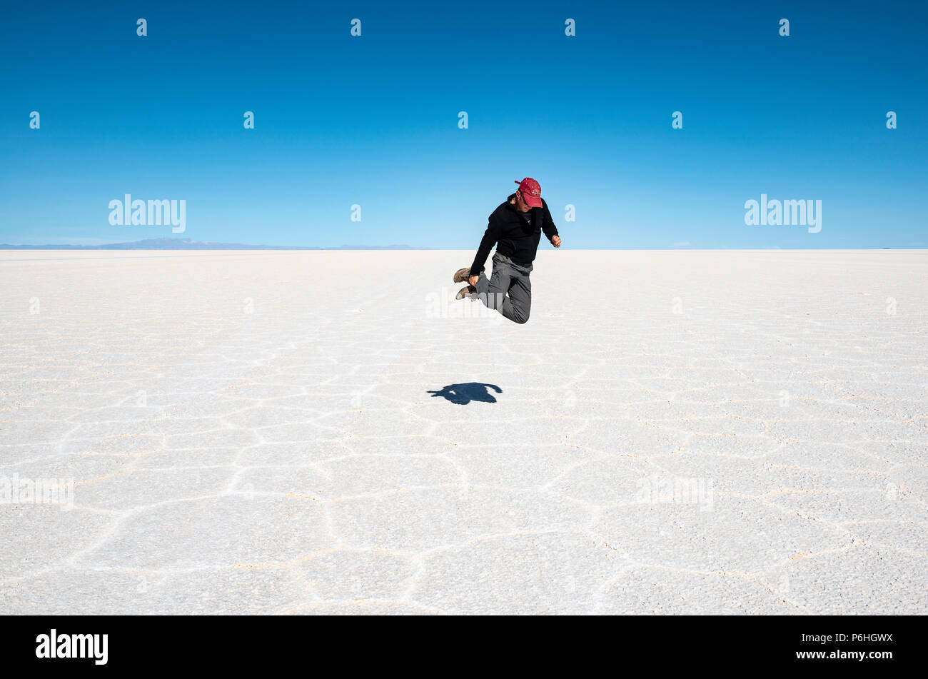 Self portrait with timer of a young adult man jumping in the Uyuni Salt Flat at high altitude in the Bolivian Andes mountain range, Bolivia. Stock Photo
