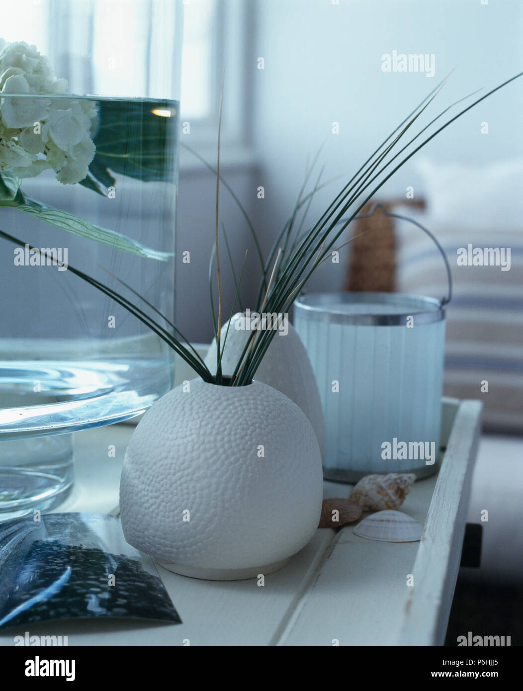 Close-up of grasses in white circular ceramic vase on white table Stock Photo
