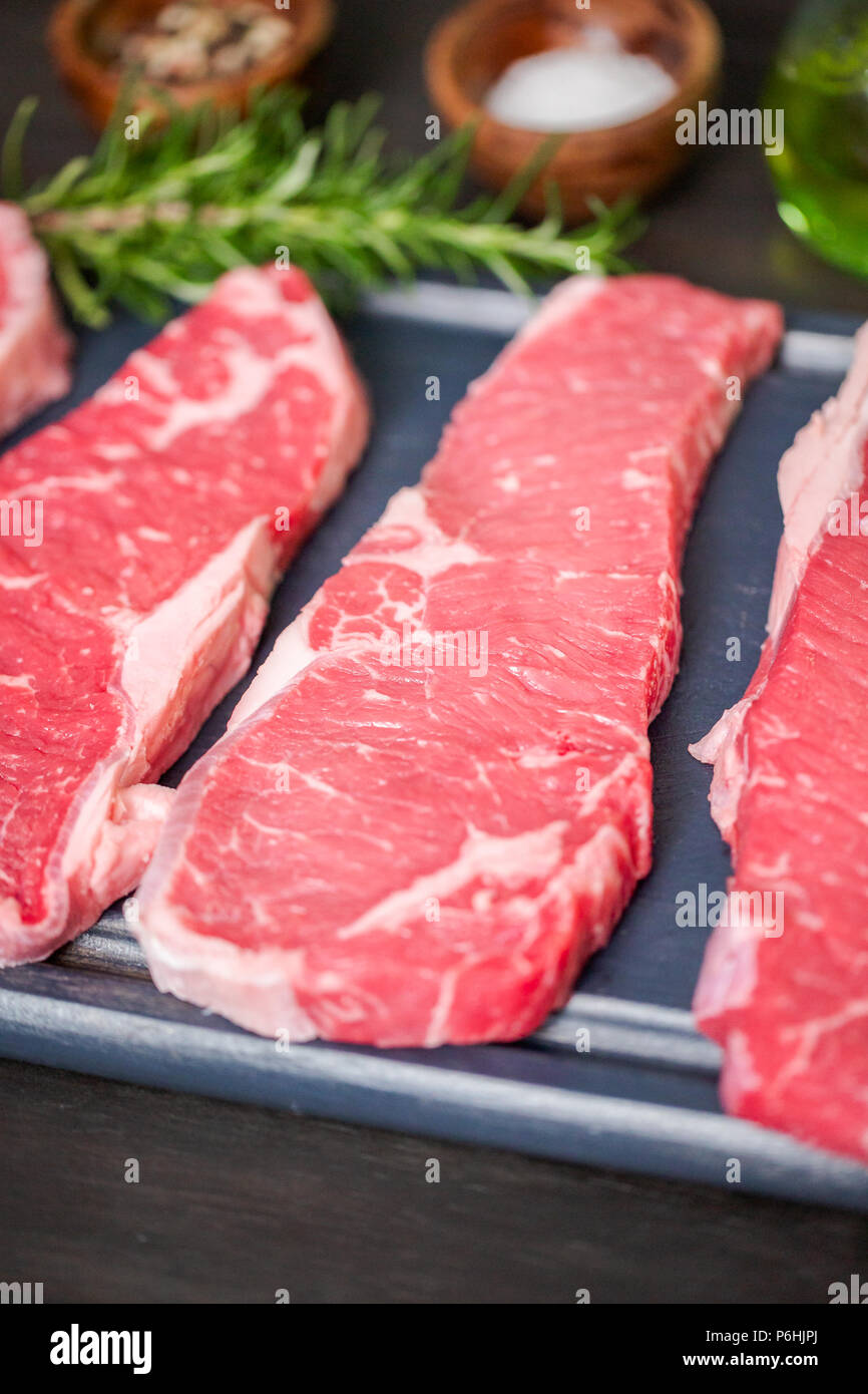 Raw New York strip steaks on a wood cutting board Stock Photo - Alamy