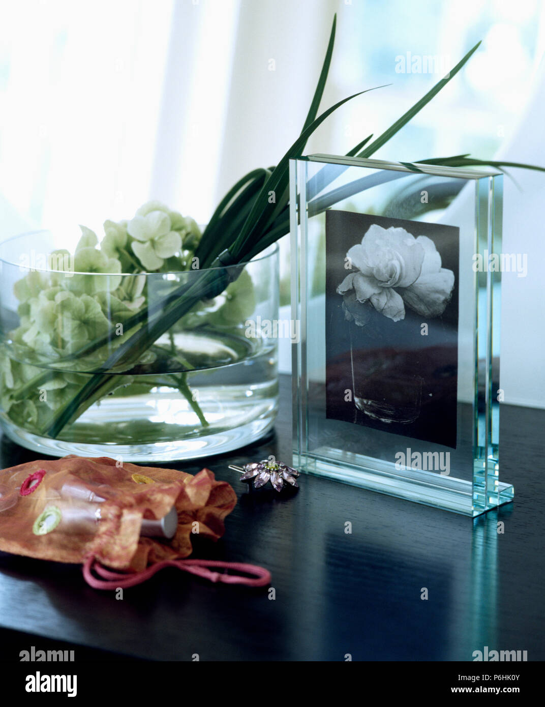 Close-up of glass photograph frame and glass dish with white flowers Stock Photo