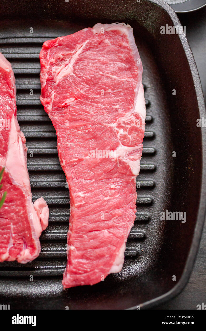 Raw New York strip steaks in cast iron frying pan Stock Photo Alamy