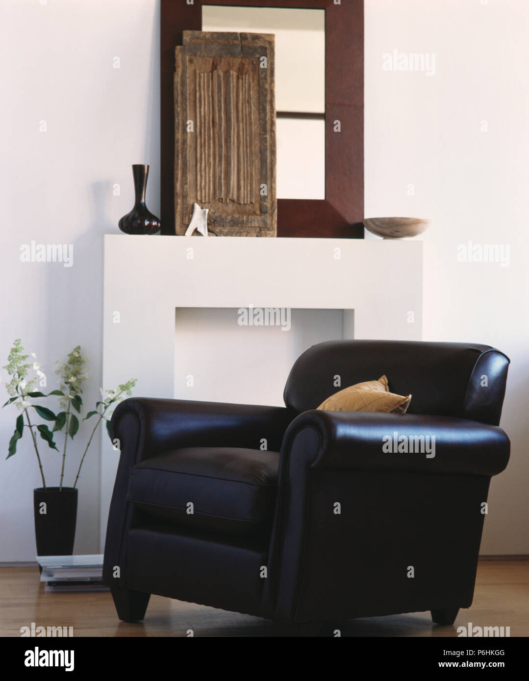 Black Leather Armchair Beside Simple White Fireplace With Mirror